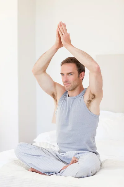 Člověk cvičí jógu na posteli — Stock fotografie