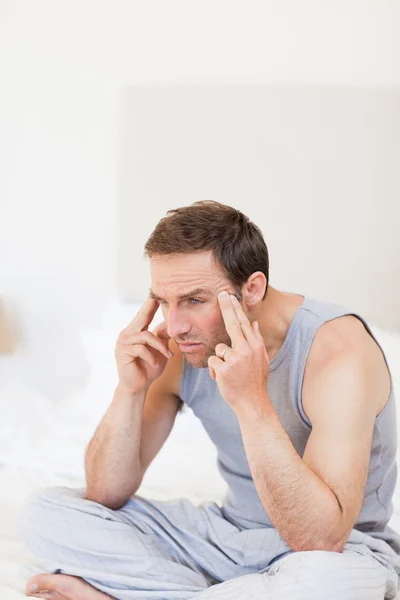 Thoughtful man sitting on his bed — Stock Photo, Image