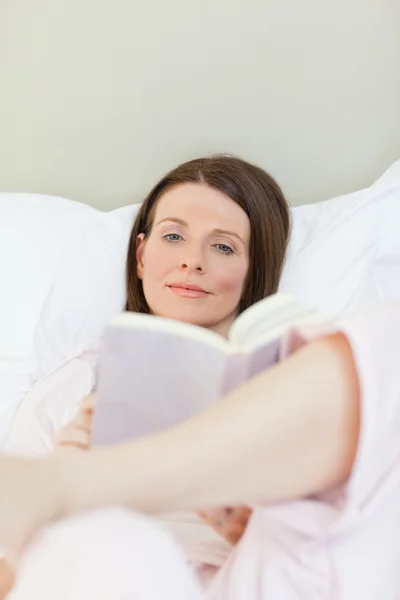 Kvinna läser en bok om hennes säng — Stockfoto