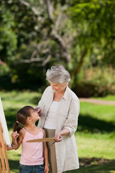 Grandmother and her granddaughter painting in the garden — Stock Photo, Image