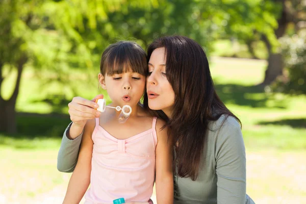 Fille soufflant des bulles avec sa mère dans le parc — Photo