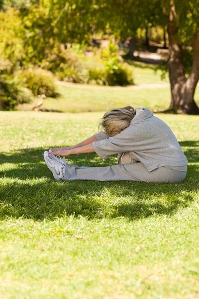 Mogen kvinna gör hennes sträcker i parken — Stockfoto