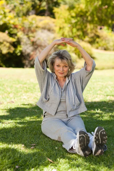 Senior woman doing her streches in the park — Stock Photo, Image