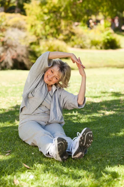 Senior woman doing her streches in the park — Stock Photo, Image