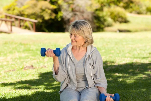 Pensionerad kvinna gör hennes övningar i parken — Stockfoto