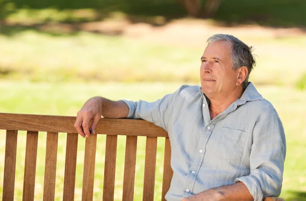 Starší muž sedí na lavičce — Stock fotografie