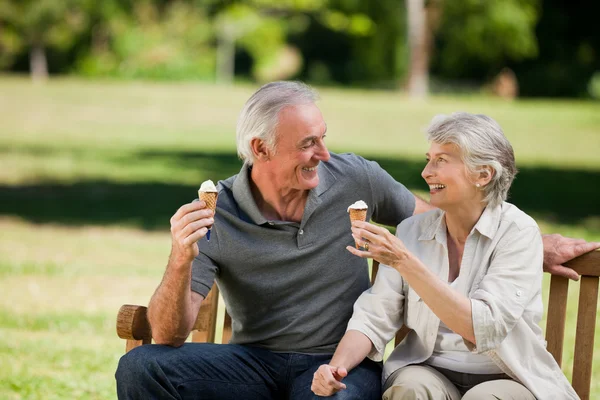 Старшая пара ест мороженое на скамейке — стоковое фото