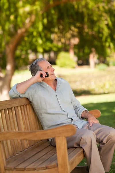 中高年の男性が公園で電話をかける — ストック写真
