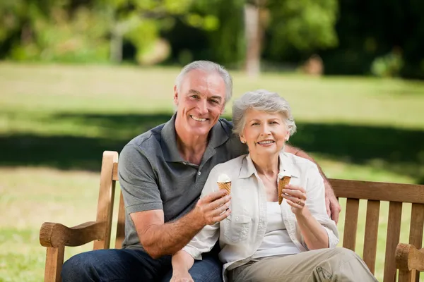 Äldre par äta en glass på en bänk — Stockfoto
