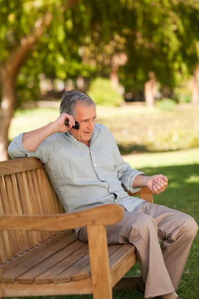 Mature man phoning in the park — Stock Photo, Image