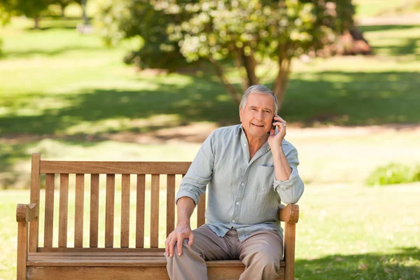Homem reformado a telefonar no parque — Fotografia de Stock