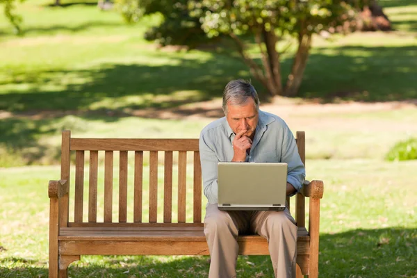 Ηλικιωμένος άνδρας που εργάζονται σε φορητό υπολογιστή του στο πάρκο — Φωτογραφία Αρχείου