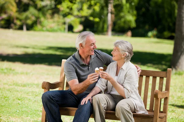 Senior couple eating an ice cream on a bench — Stock Photo, Image