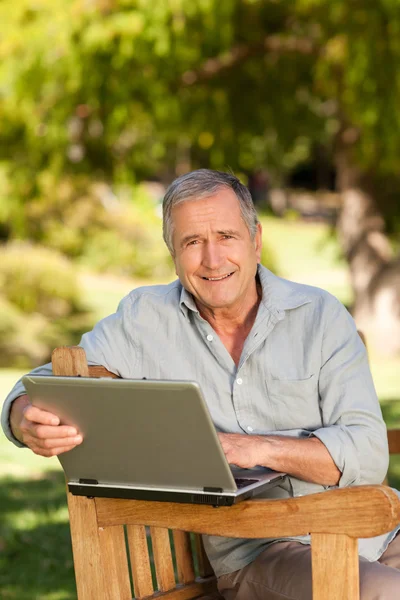 Homem aposentado trabalhando em seu laptop no parque — Fotografia de Stock