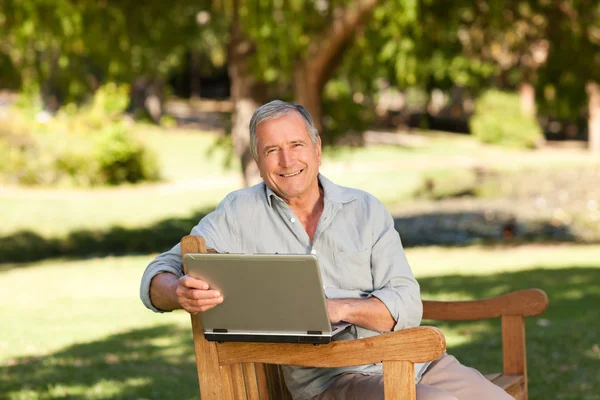 Gepensioneerde man aan het werk op zijn laptop in het park — Stockfoto