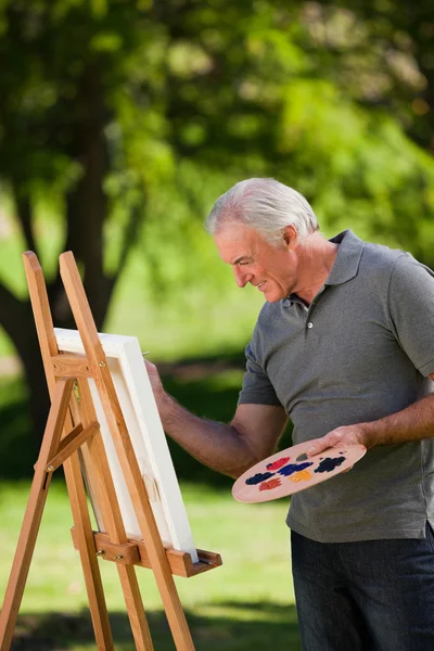 Старший чоловік малює в саду — стокове фото