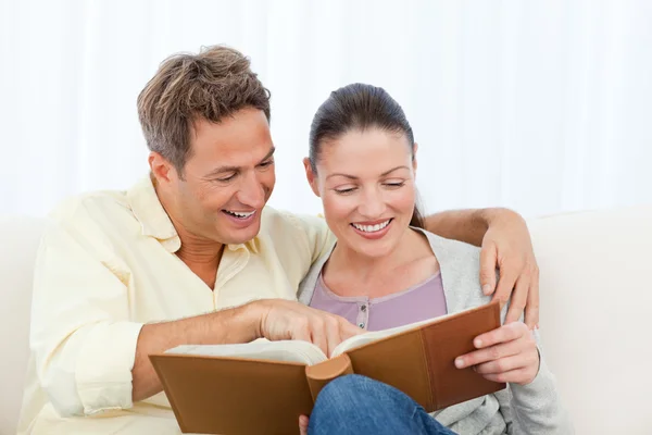 Couple smiling while looking at pictures on a photo album — Stock Photo, Image