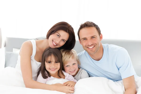 Porträt einer glücklichen Familie auf dem Bett Stockbild