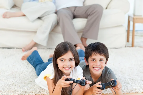 Niños jugando videojuegos mientras los padres están hablando —  Fotos de Stock