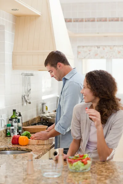 Beautiful woman looking at her husband who is cooking — Stock Photo, Image
