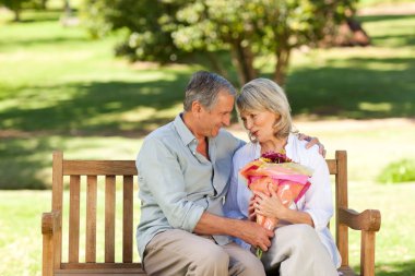 Mature man offering flowers to his wife clipart