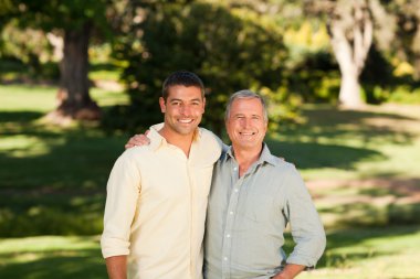 Father with his son looking at the camera in the park clipart