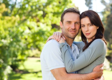 Radiant couple hugging in the park clipart