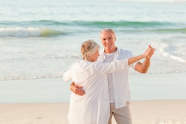 Senior couple dancing on the beach clipart