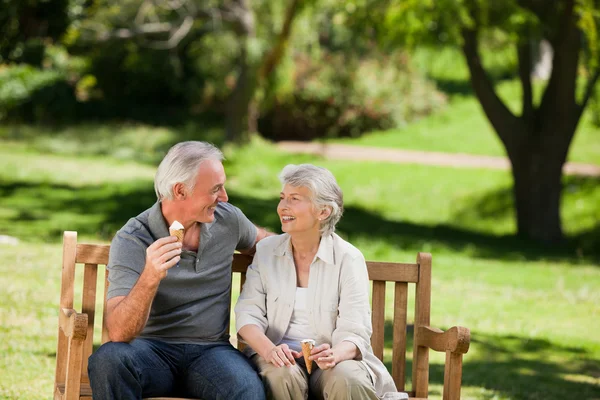Äldre par äta en glass på en bänk — Stockfoto