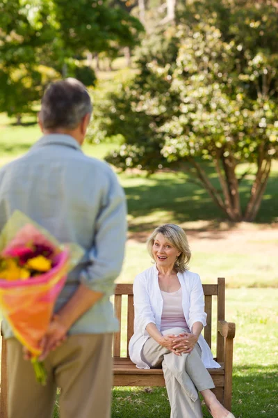 Зрелый мужчина приносит цветы своей жене — стоковое фото