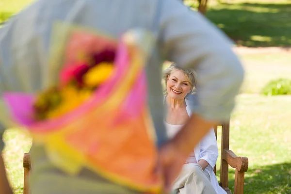 Mogen man erbjuder blommor till sin fru — Stockfoto
