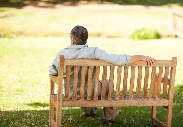 Uomo anziano seduto sulla panchina con la schiena alla telecamera — Foto Stock