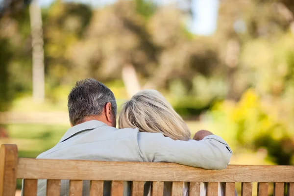 Elderly couple sitting on the bench with their back to the camer — Stock Photo, Image