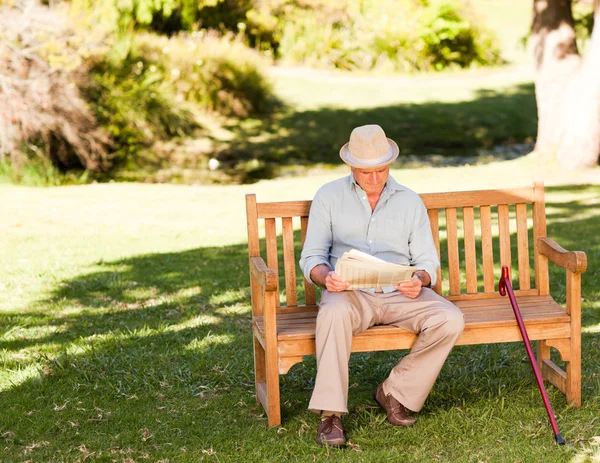 Retired man reading his newspaper on the bench — Stock Photo, Image