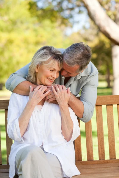 Homem idoso abraçando sua esposa que está no banco — Fotografia de Stock