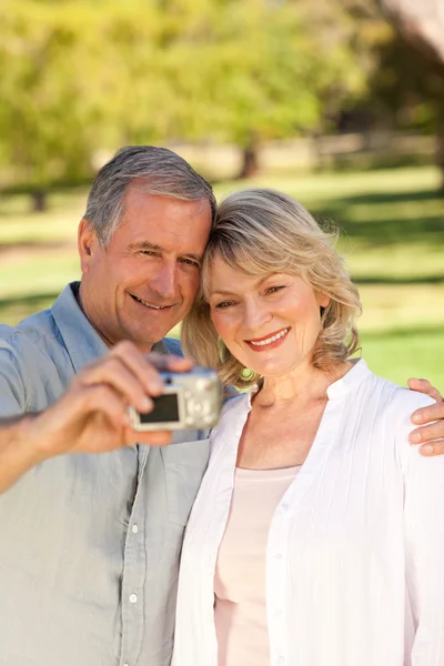Elderly couple taking a photo of themselves in the park — Stock Photo, Image
