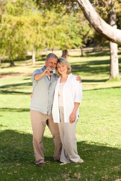 Elderly couple taking a photo of themselves in the park — Stock Photo, Image