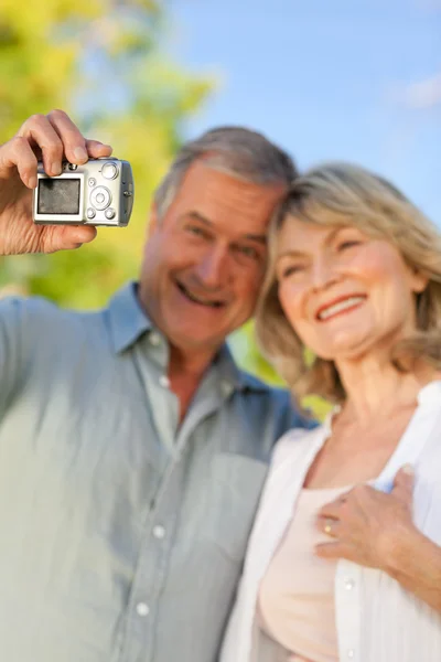 Sorrindo casal tirando uma foto de si mesmos no parque — Fotografia de Stock