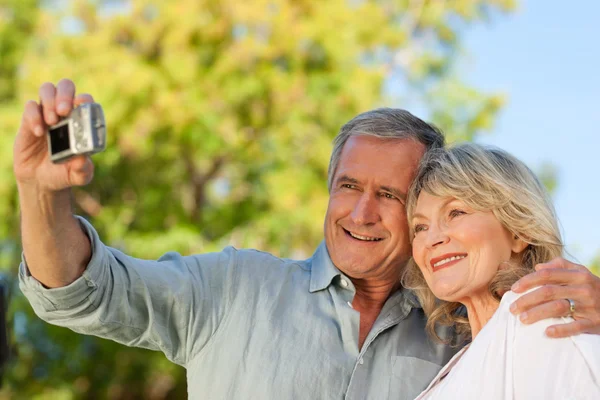 Smiling couple taking a photo of themselves in the park — Stock Photo, Image