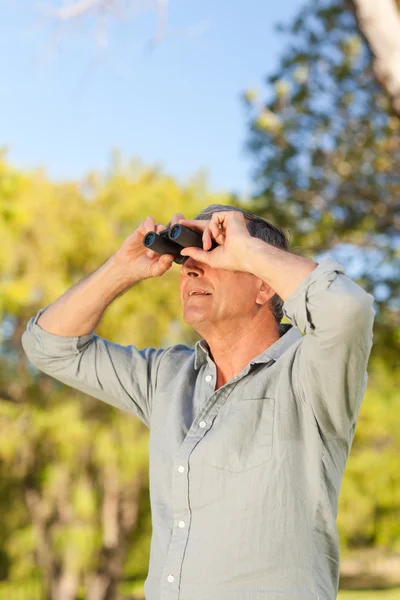 Senior man op zoek naar de hemel met zijn verrekijker — Stockfoto