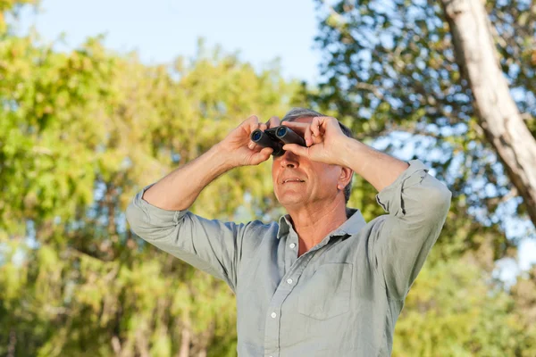 Homem sênior olhando para o céu com seus binóculos — Fotografia de Stock