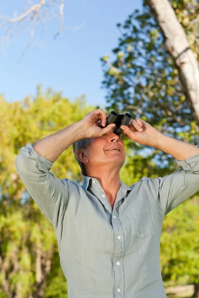 Старший чоловік дивиться на небо зі своїми біноклями — стокове фото