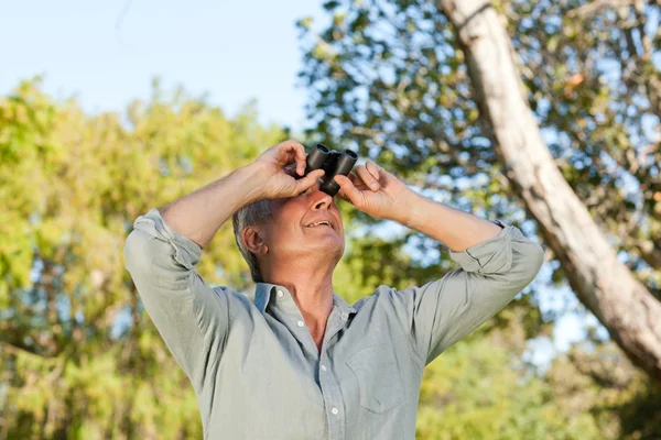 Senior man op zoek naar de hemel met zijn verrekijker — Stockfoto