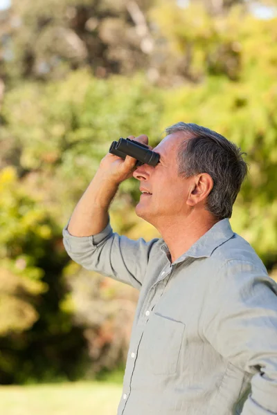 Starszy mężczyzna patrząc w niebo z lornetki — Zdjęcie stockowe