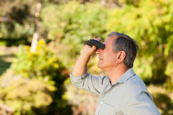 Oudere man op zoek naar de hemel met zijn verrekijker — Stockfoto