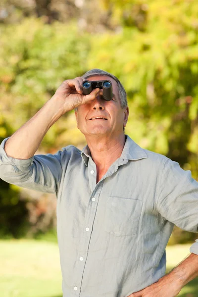 Oudere man op zoek naar de hemel met zijn verrekijker — Stockfoto