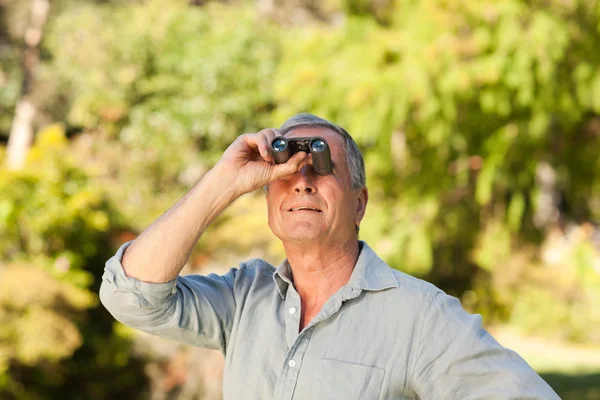 Пожилой человек смотрит в небо со своим биноклем — стоковое фото