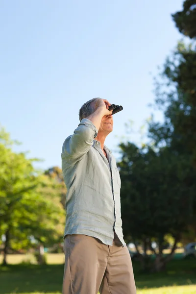 Пожилой человек смотрит в небо со своим биноклем — стоковое фото
