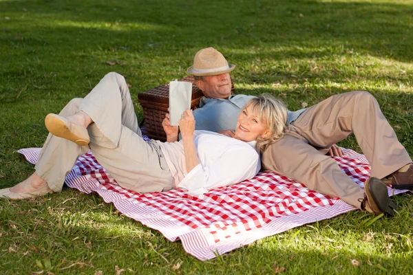 Vrouw leest terwijl haar echtgenoot is slapen in het park — Stockfoto