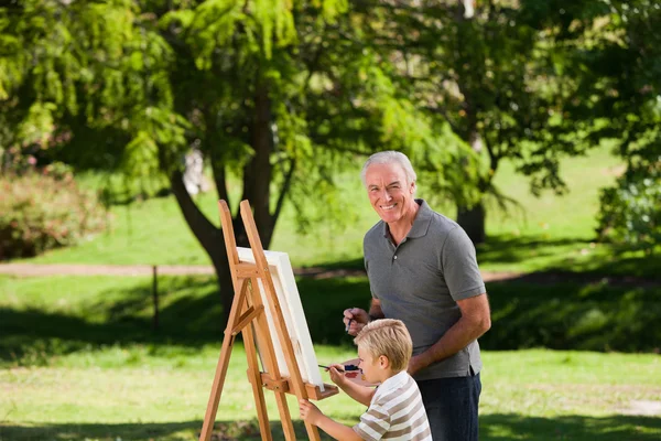 Grootvader en zijn kleinzoon schilderij in de tuin — Stockfoto